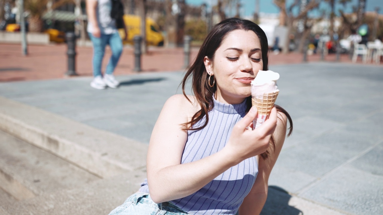 开朗的黑发女人在吃冰淇淋视频素材
