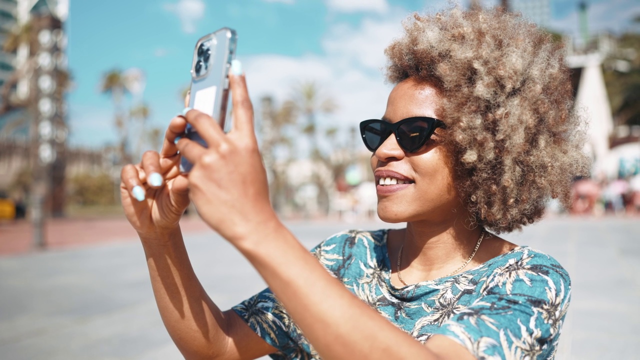欢快的非洲灰色头发的女人戴着太阳镜拍摄街道的视频移动视频素材