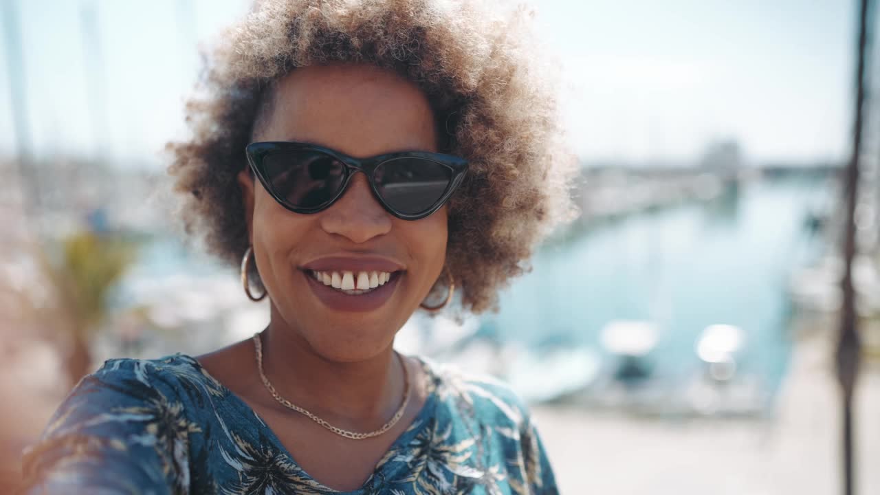 快乐的非洲灰白头发的女人对着镜头挥手，指着游艇视频素材