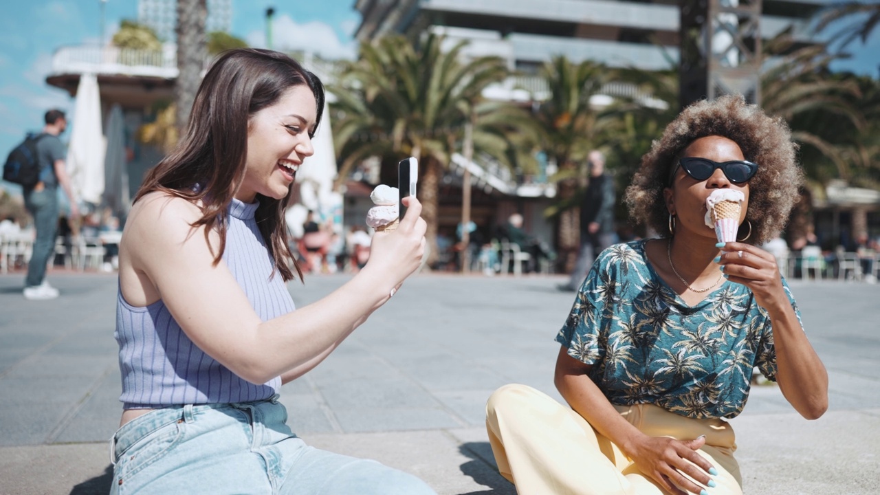 两名微笑的多民族妇女用手机摄像头拍下了冰淇淋的视频视频素材