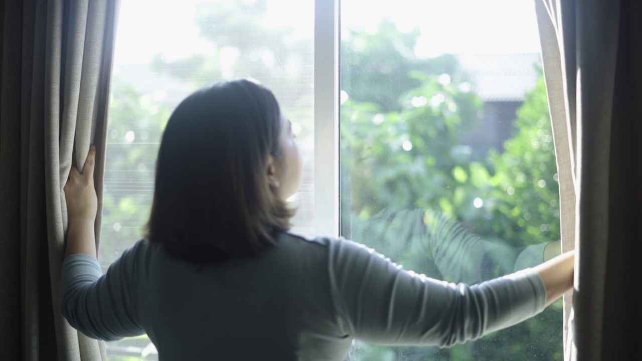 一个女人正在打开阳台的窗户视频素材