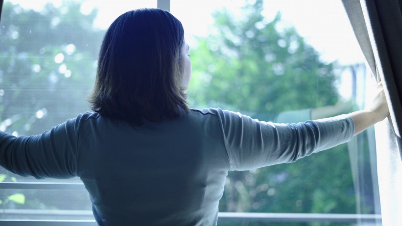 一个女人正在打开阳台的窗户视频素材