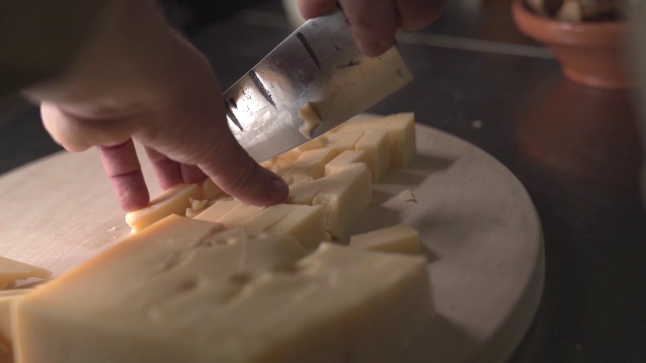 一个男人在砧板上切奶酪，特写视频素材