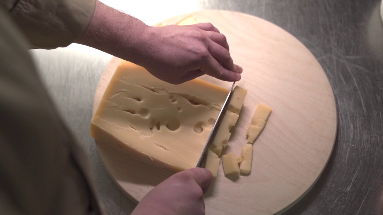 一个男人在砧板上切奶酪，特写视频素材