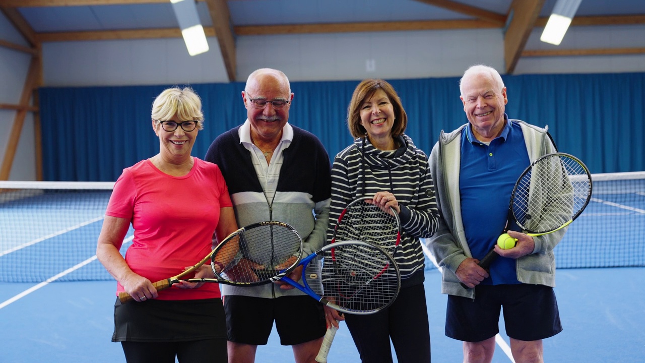 活跃的老年情侣一起站在室内网球场视频下载