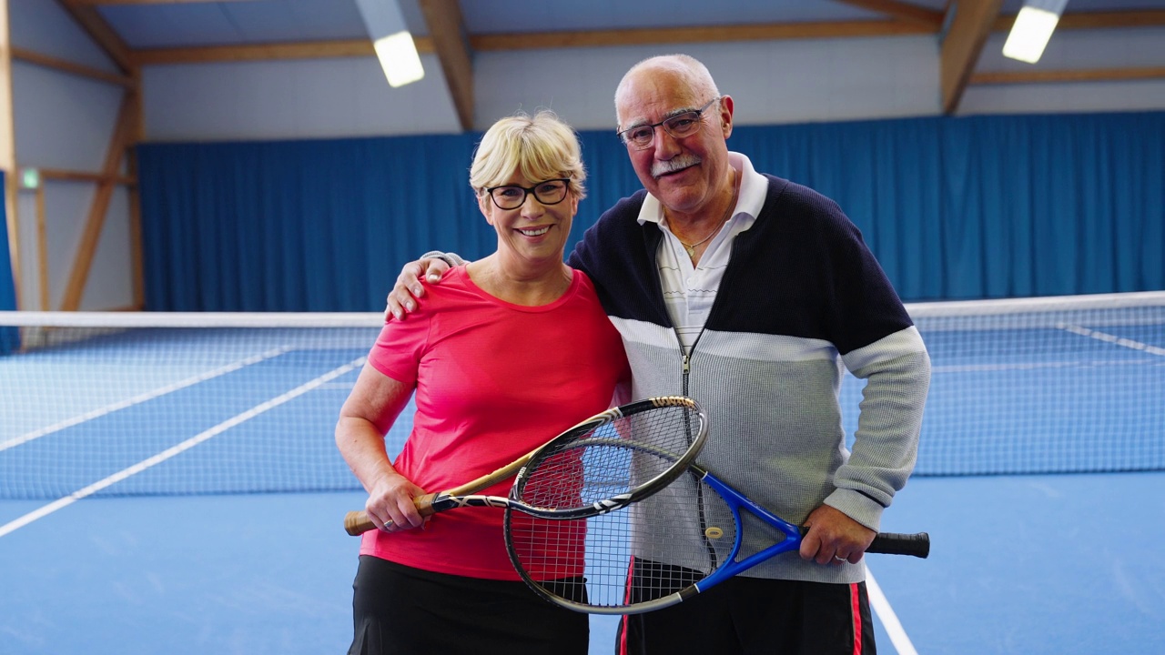 幸福的高级夫妇的肖像网球运动员一起站在硬地球场视频下载