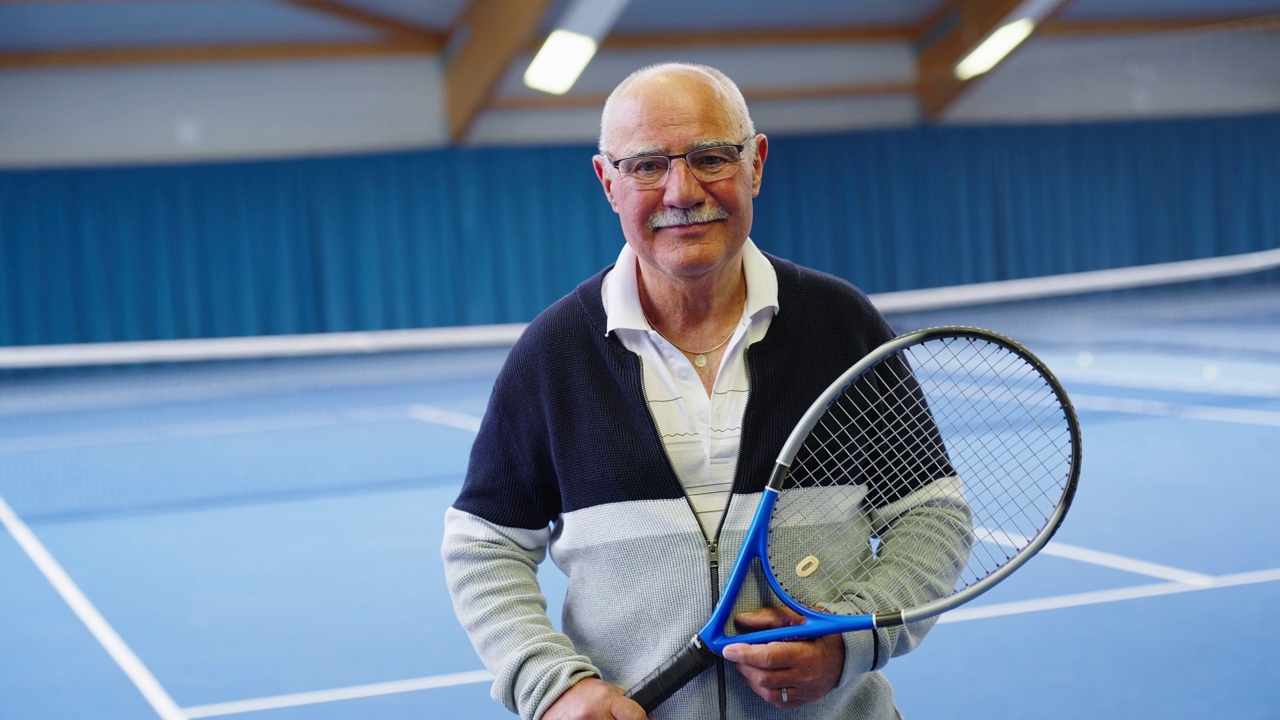 快乐的老人拿着网球拍站在网球场上视频下载