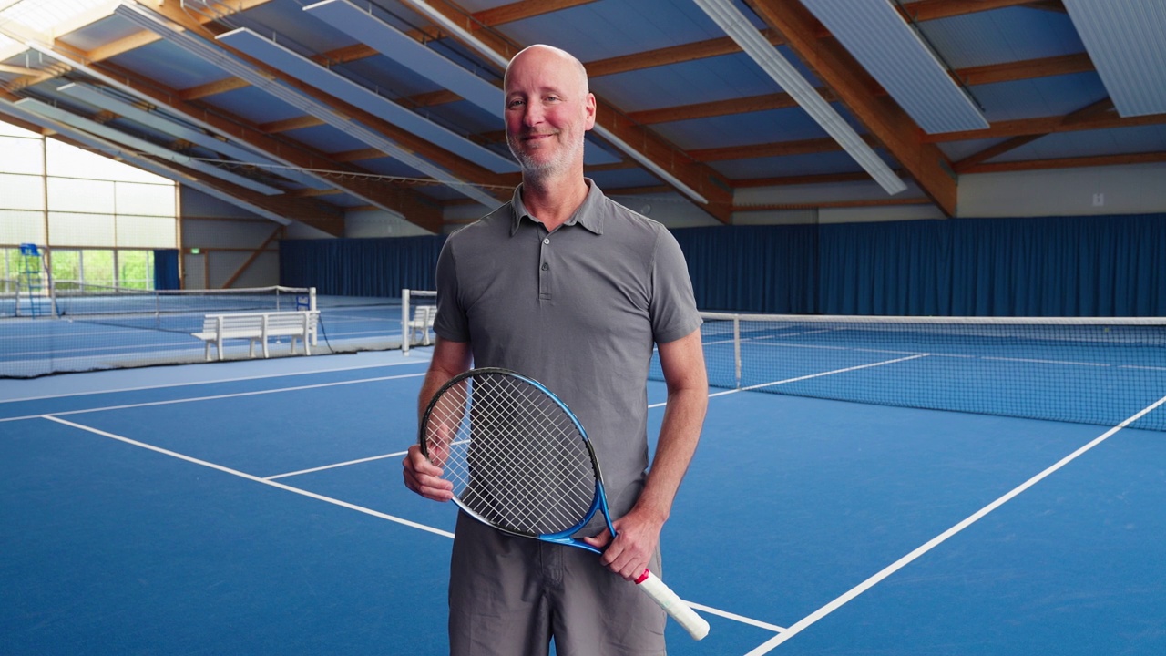 一个快乐成熟的男性网球运动员在室内球场的肖像视频素材