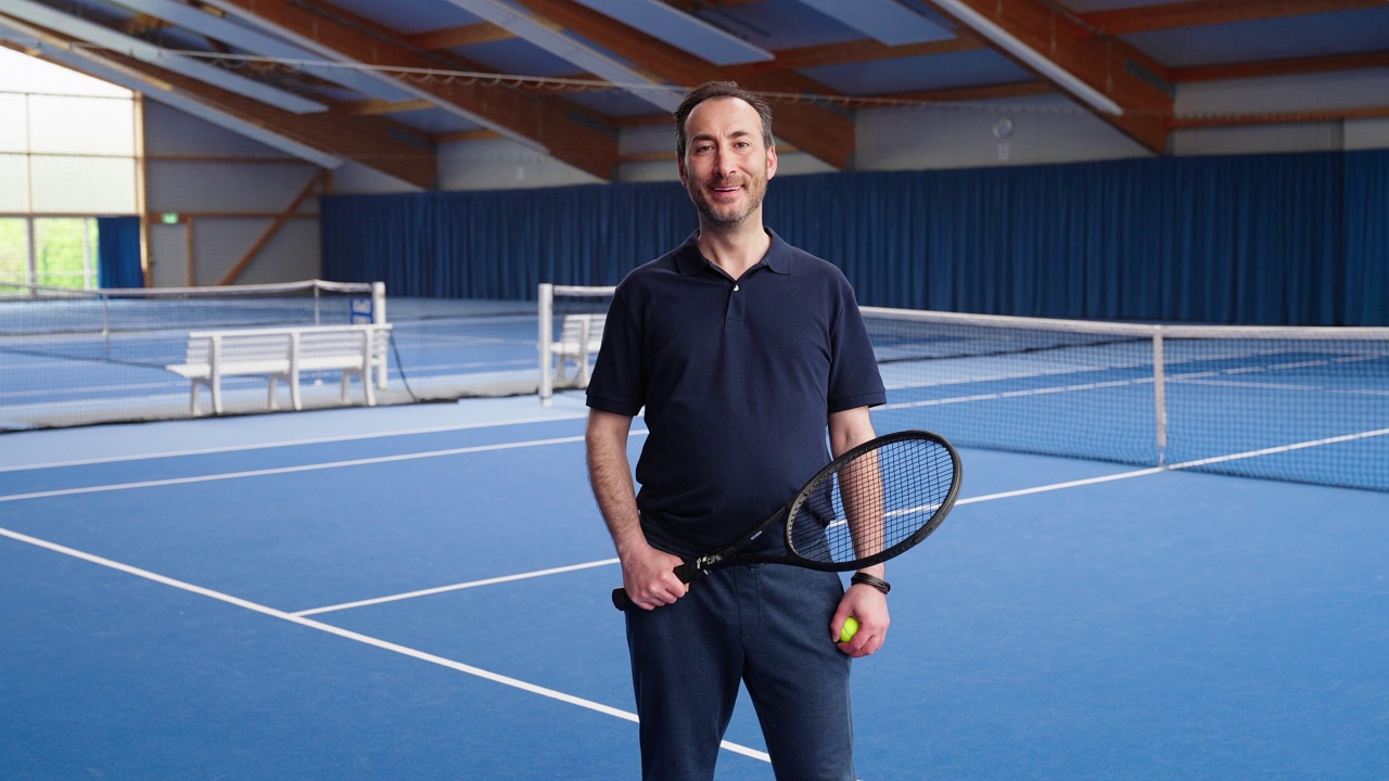 一个快乐成熟的男人拿着网球拍和网球站在球场上视频素材