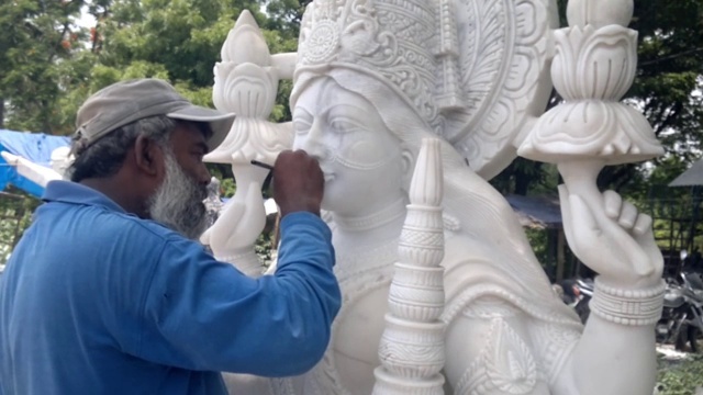 印度工匠雕刻传统印度教女神拉克希米或拉克希米白色大理石雕塑或雕像出售，使用锤子和凿子，手移动。视频下载