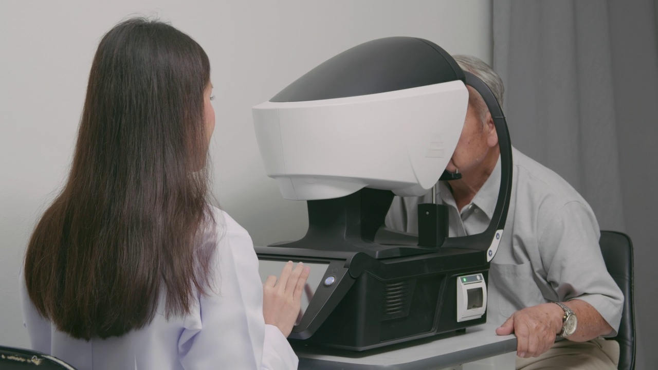一名亚洲老人正在接受一台医疗机器的眼睛检查。视频下载