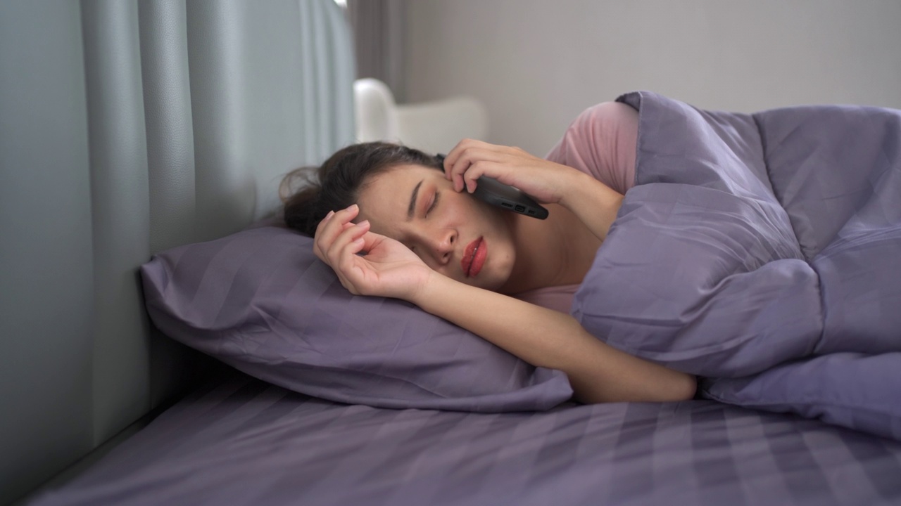 女人用智能手机闹钟睡觉。视频素材