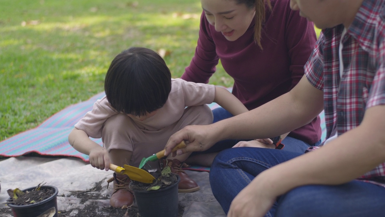父亲和母亲教他们的两个儿子如何用厨房和花园的垃圾制作有机肥料视频素材