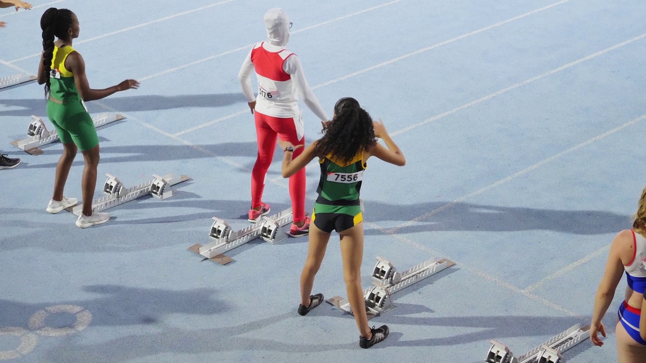 女子田径运动员在起跑线上伸展视频下载