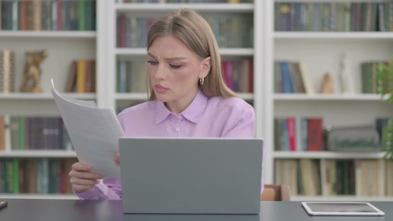 拿着笔记本电脑的女人一边看文件一边庆祝成功视频素材