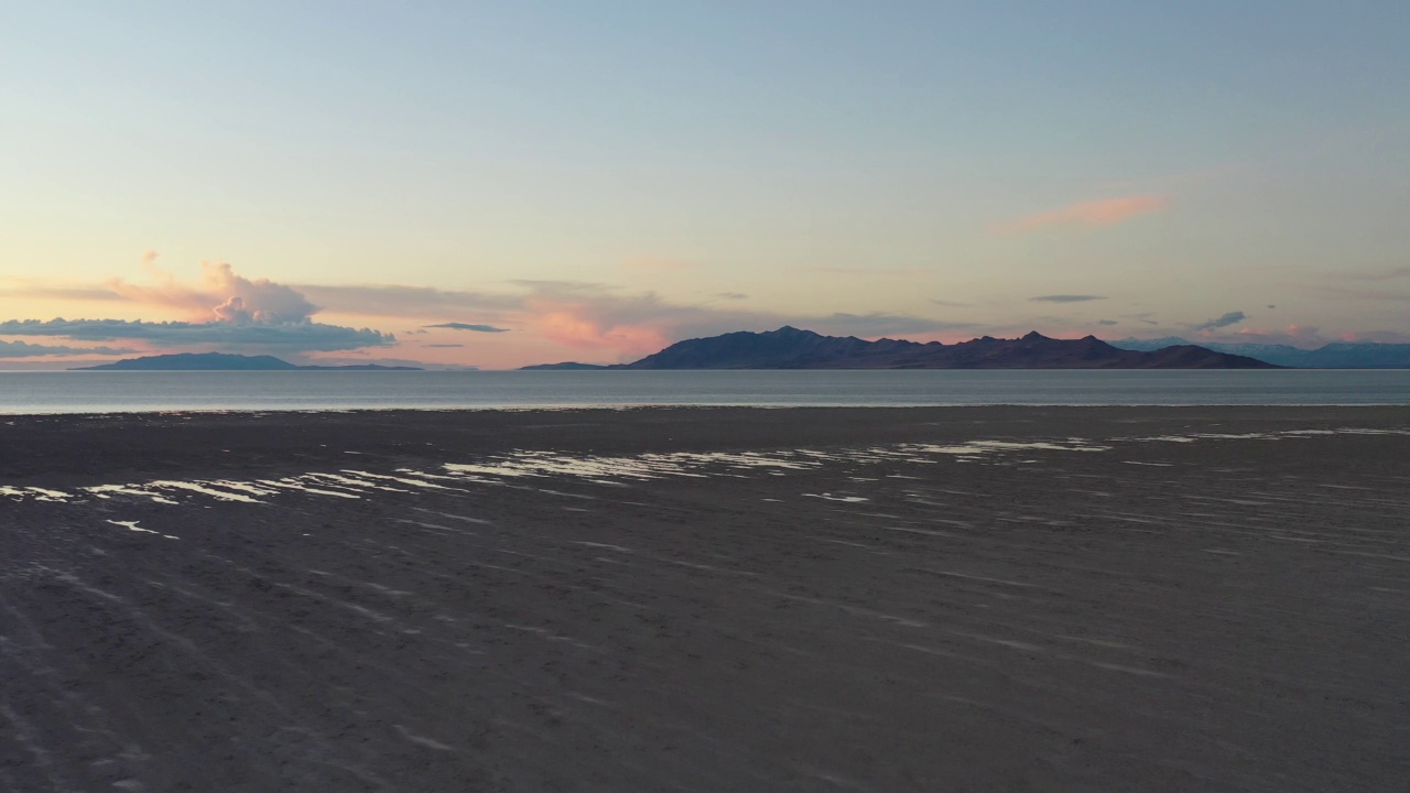 无人机在日落时飞越沙滩和湖泊视频下载