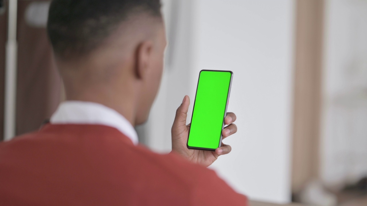 非洲人手持绿色屏幕智能手机的后视图视频素材