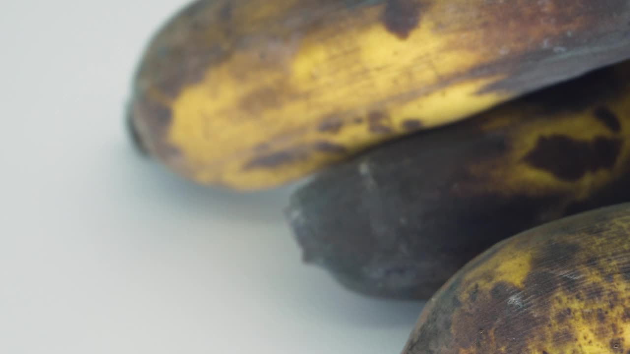 成熟香蕉的宏观图像与孤立的棕色斑点在白色的背景。视频素材