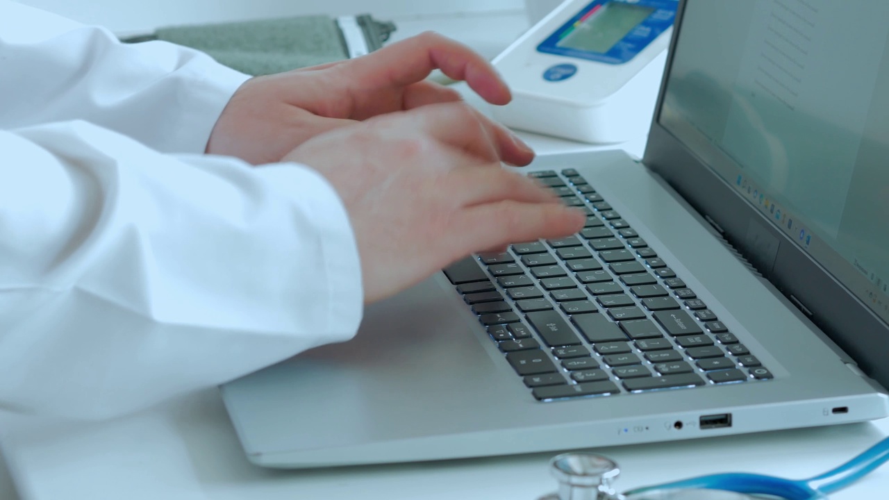 医学的概念，医生的工作，一个穿着白大褂的人的手在笔记本电脑上打印文本或写一个药物配方，在一个白色的桌子上一个测量仪视频素材