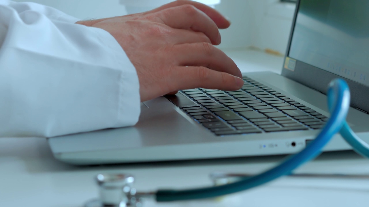 前景中的风扇内窥镜，一个男人的手在键盘上打印文字，一份医学检查，选择性聚焦视频素材
