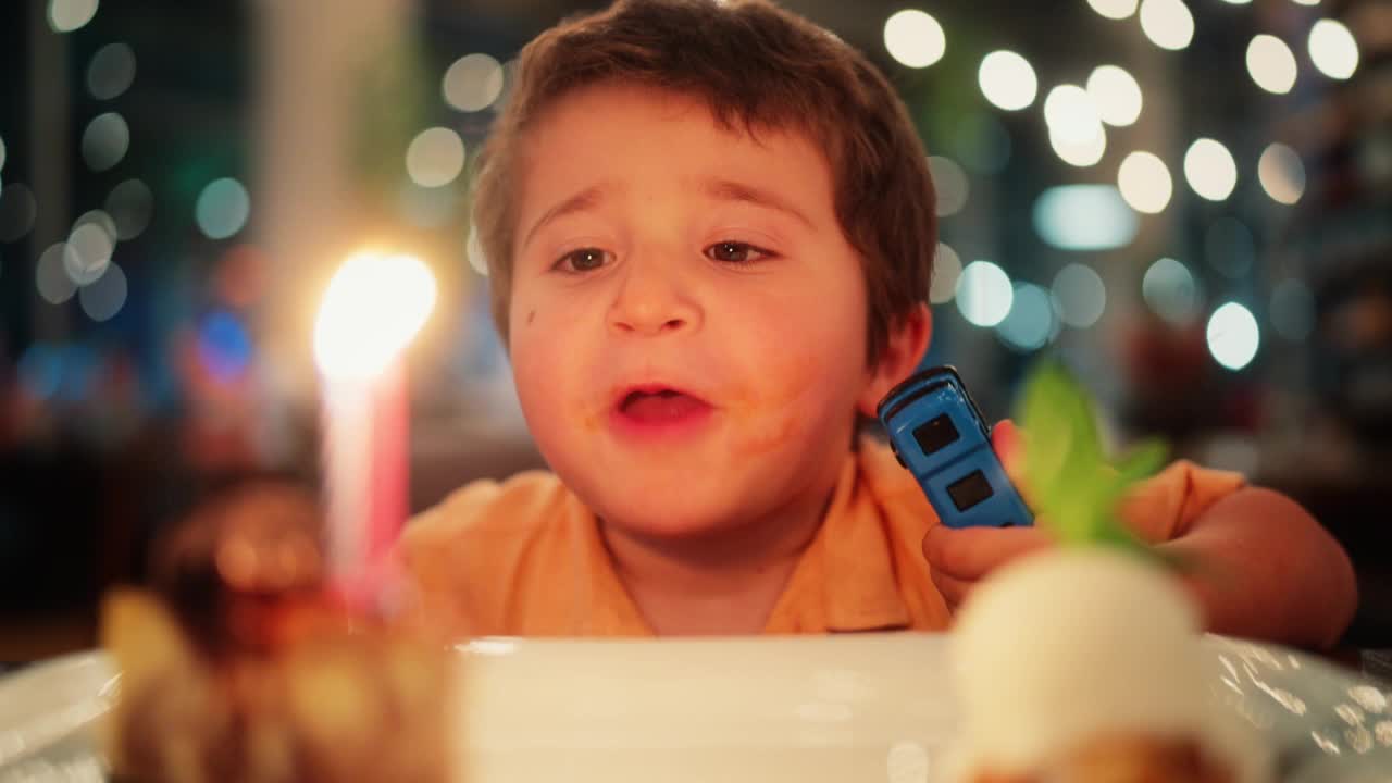 小男孩想吹灭生日蛋糕上的蜡烛视频素材