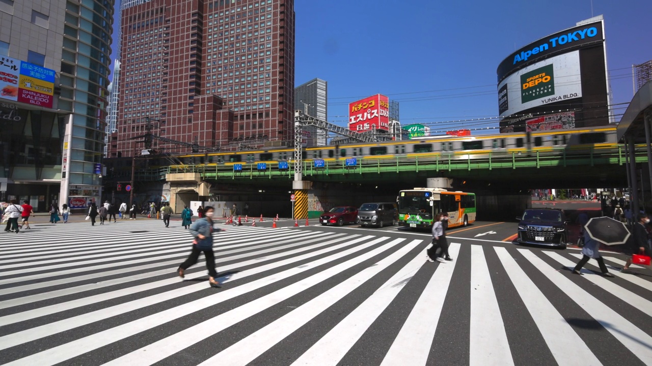 在日本东京新宿车站西出口附近，人群穿过长长的人行横道视频素材