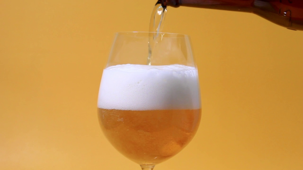 倒啤酒的慢动作，以玻璃特写的角度对黄色BG视频素材