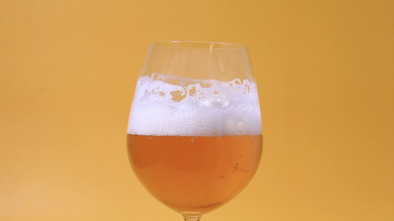 在黄色背景上展示一杯啤酒的特写角度视频素材
