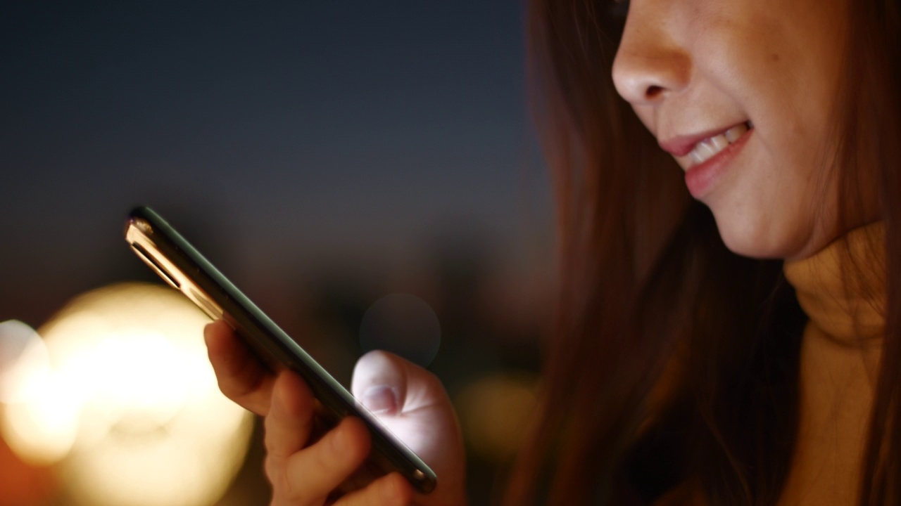 一名女子在城市的夜晚使用智能手机视频素材