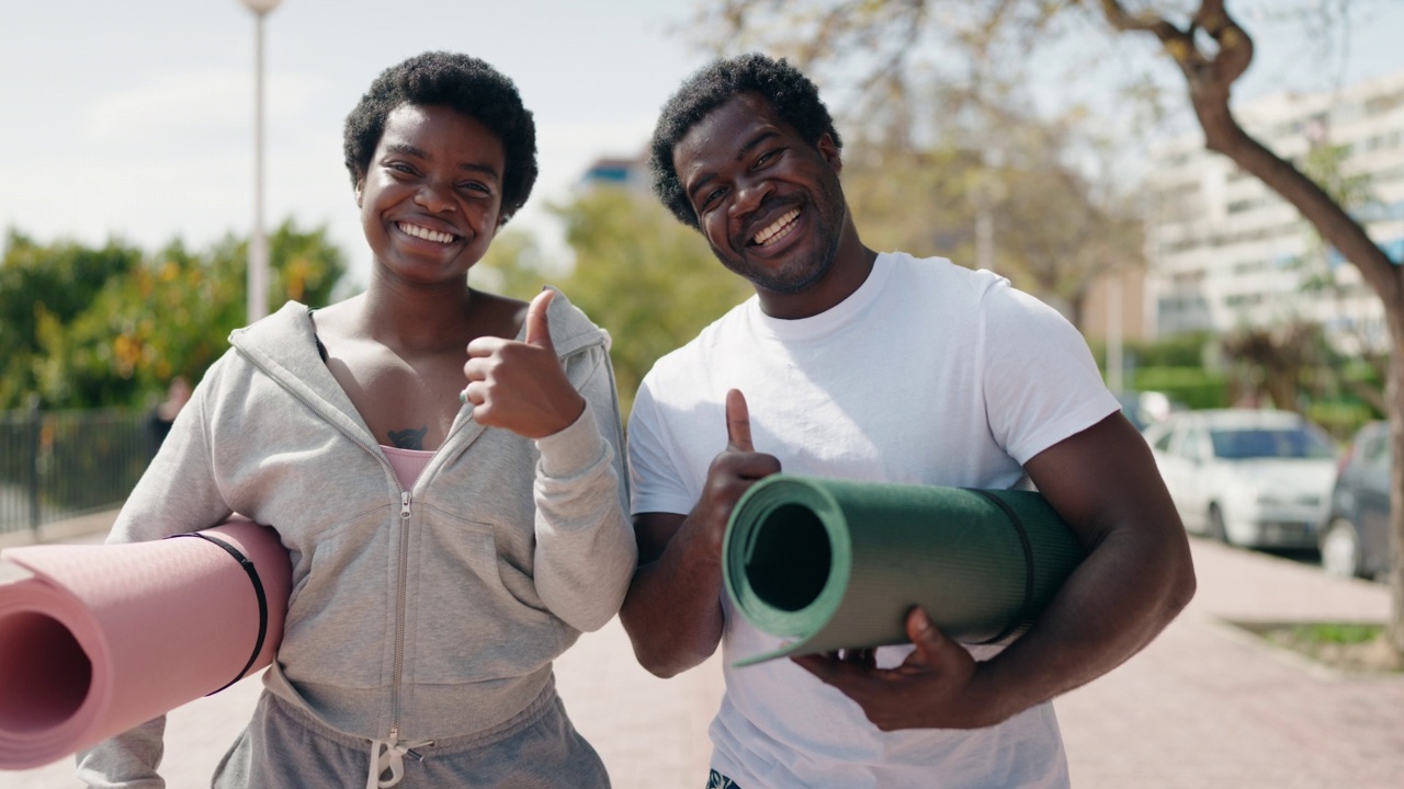 非洲裔美国男女夫妇在街上举着瑜伽垫做ok手势视频下载