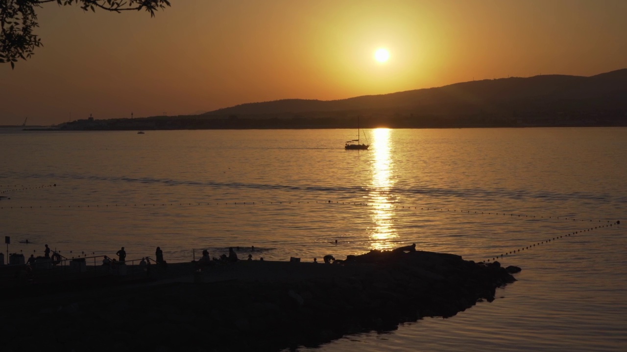 黑海海岸的日落。小船漂浮在海面上，反射着夕阳的阳光。田园诗般的度假胜地的宁静背景视频素材