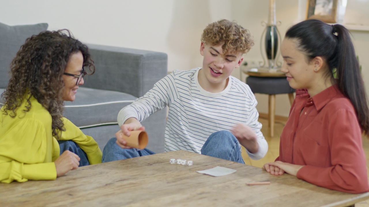 快乐的补丁家庭玩快艇骰子游戏在客厅的桌子上视频素材