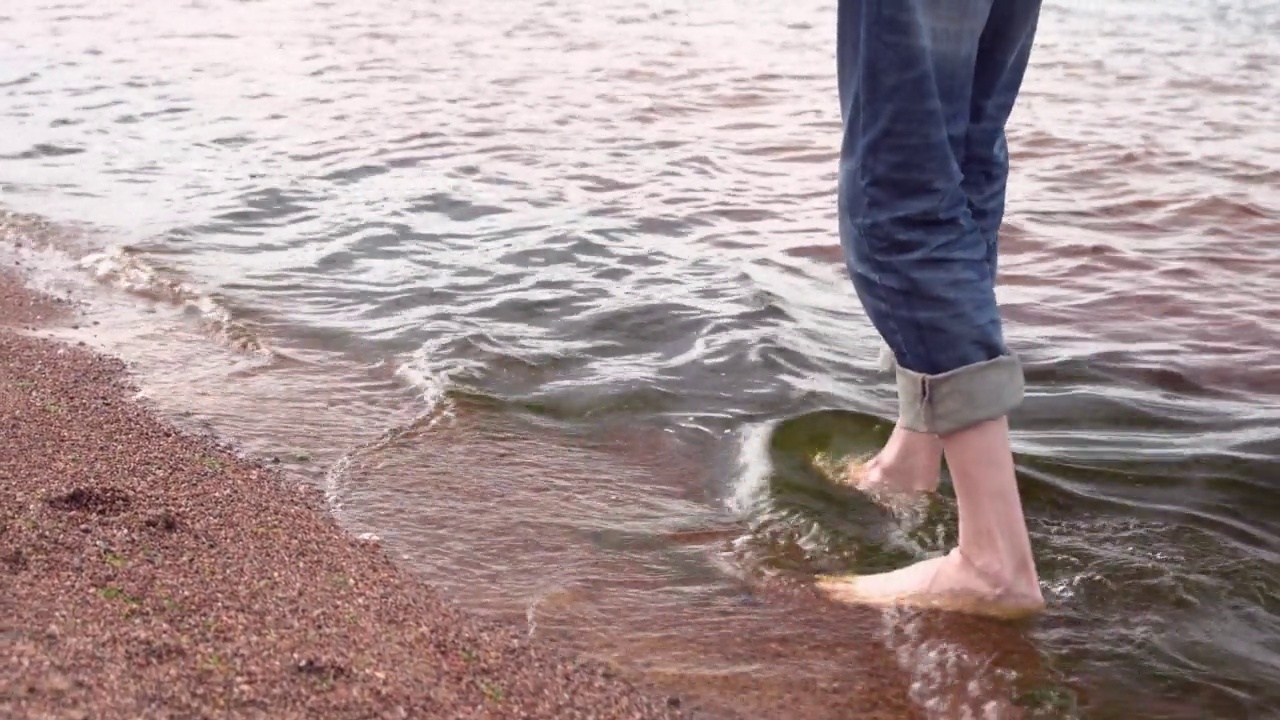 一个穿着蓝色牛仔裤的瘦子的腿在水上行走视频素材