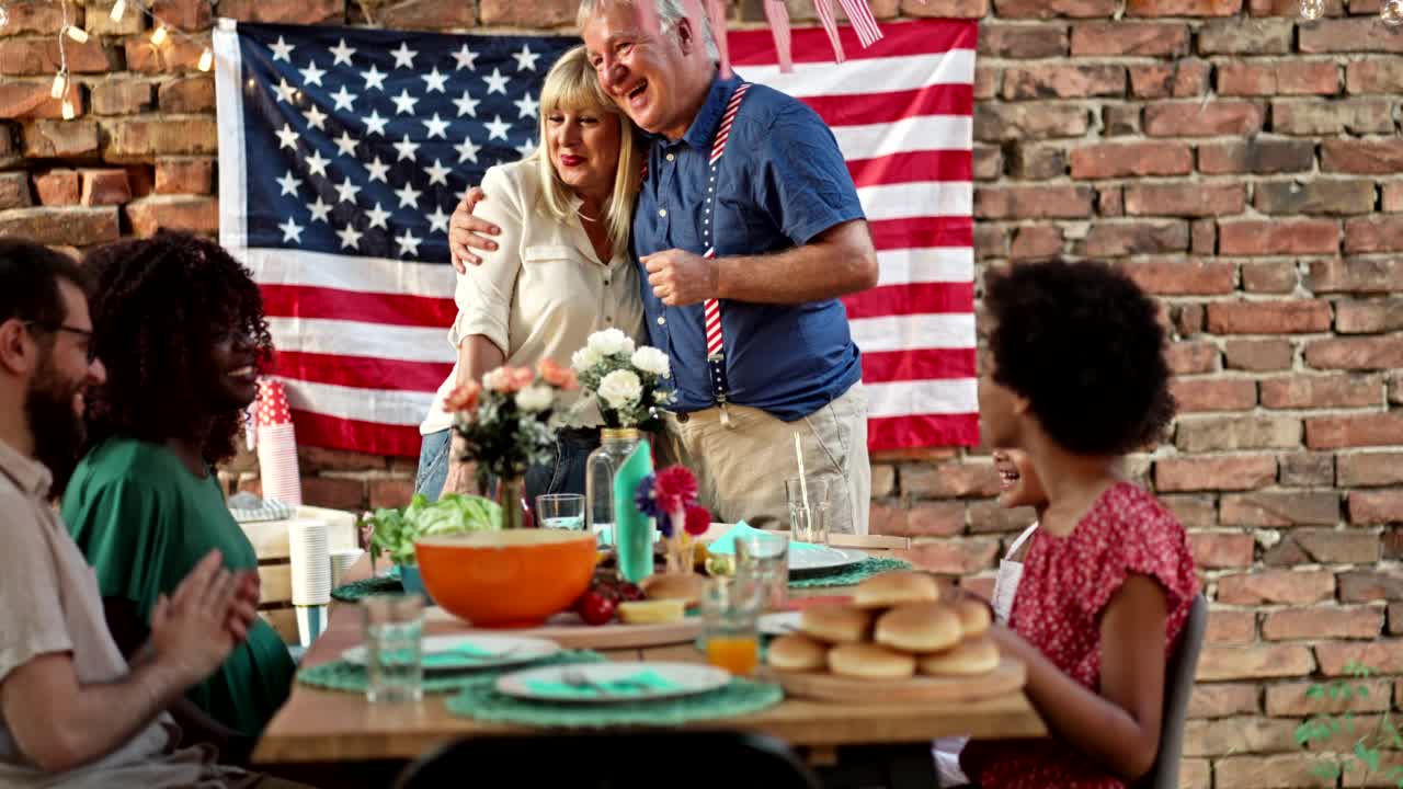 快乐的多民族家庭在餐桌上庆祝户外7月4日聚会视频素材