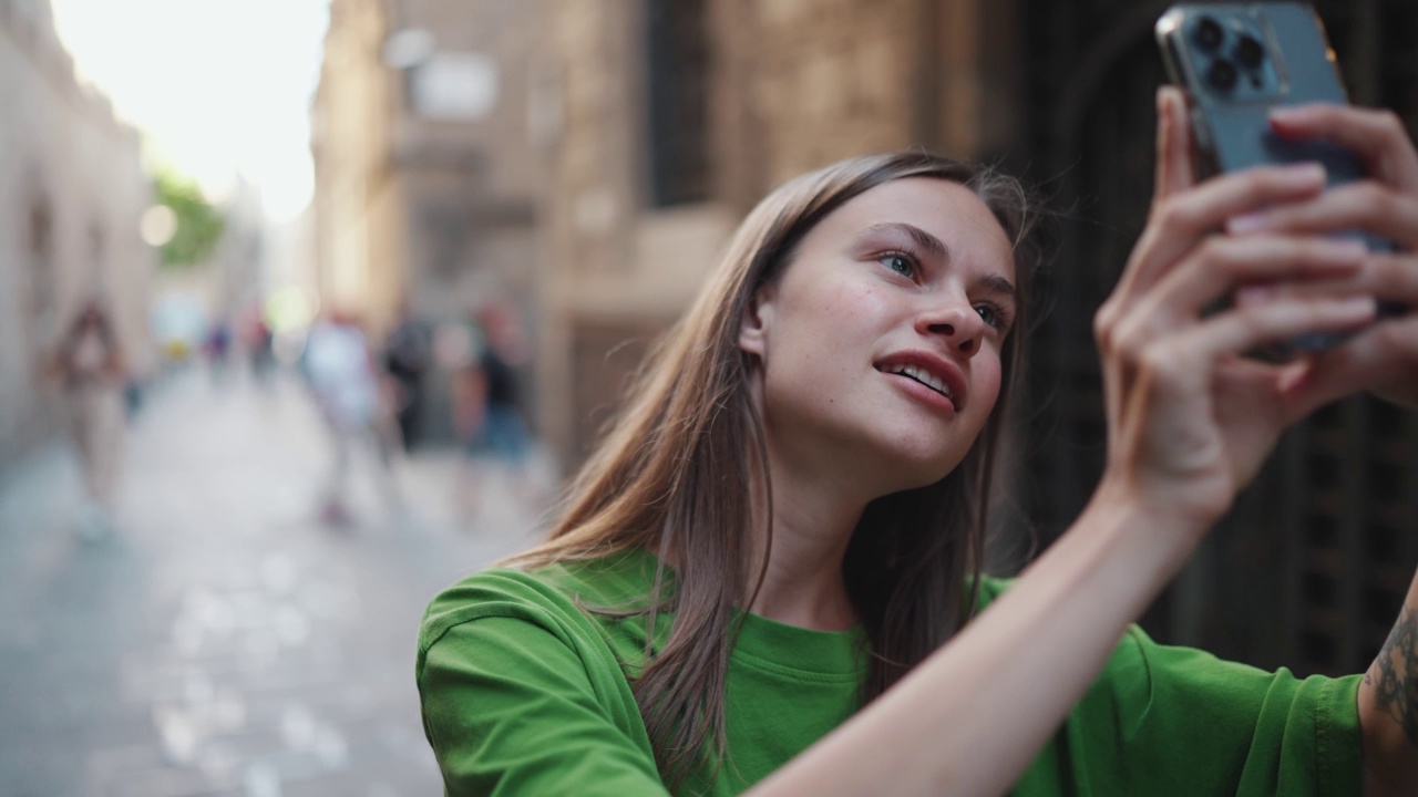 积极的金发女人通过电话拍摄街道照片视频素材