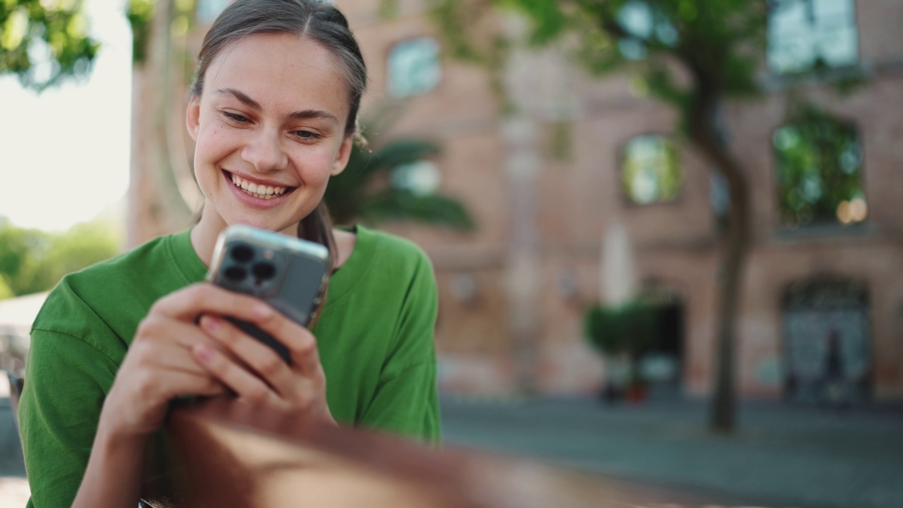 大笑的金发女人在户外用手机发短信视频素材