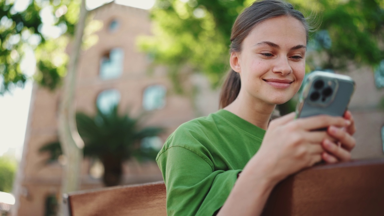 乐观的金发女人在长椅上用手机发短信视频素材
