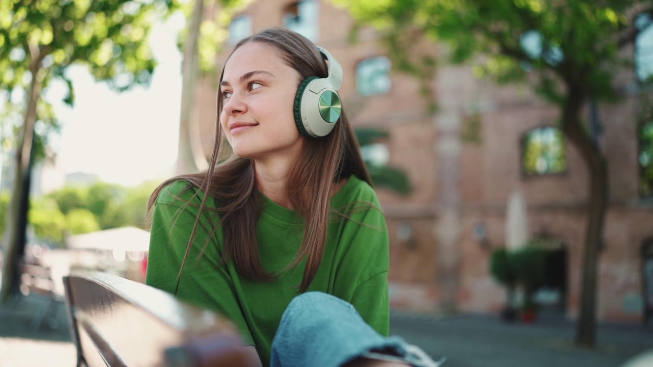 放松的女人在户外戴着耳机听音乐视频素材