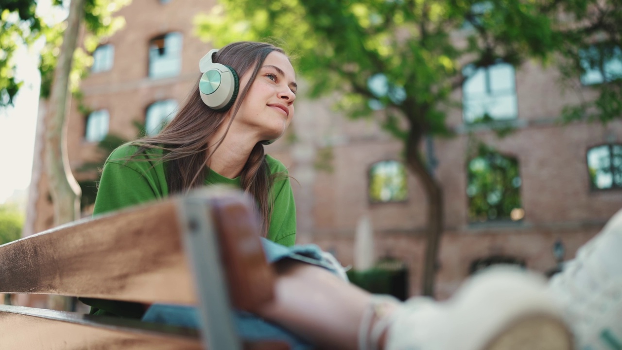 积极的女人在户外戴着耳机听音乐视频素材
