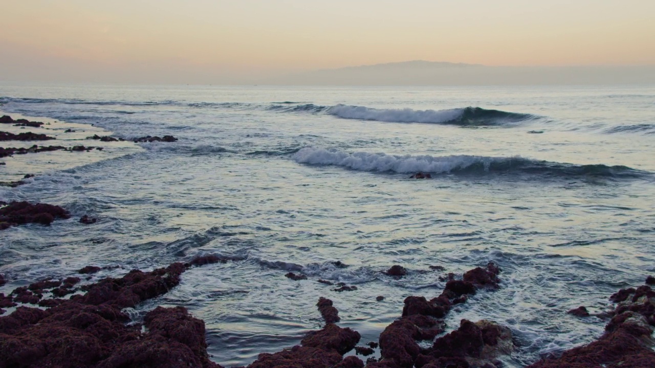 拉戈梅拉岛的日落美景。日落时分，大西洋海浪与藻类一起撞击火山石。低潮。红色海藻。视频素材