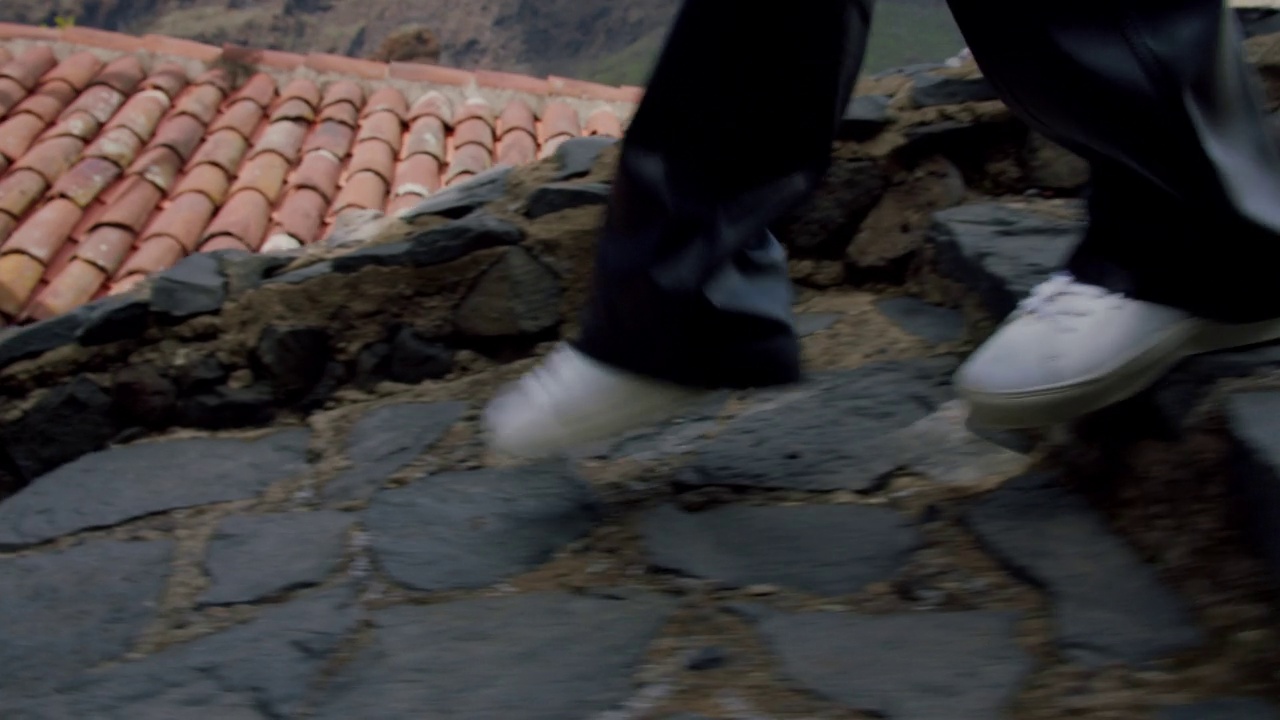 特写镜头:在加那利岛特内里费岛马斯卡峡谷村，穿着白色运动鞋的女人的脚走在石头小路上视频素材