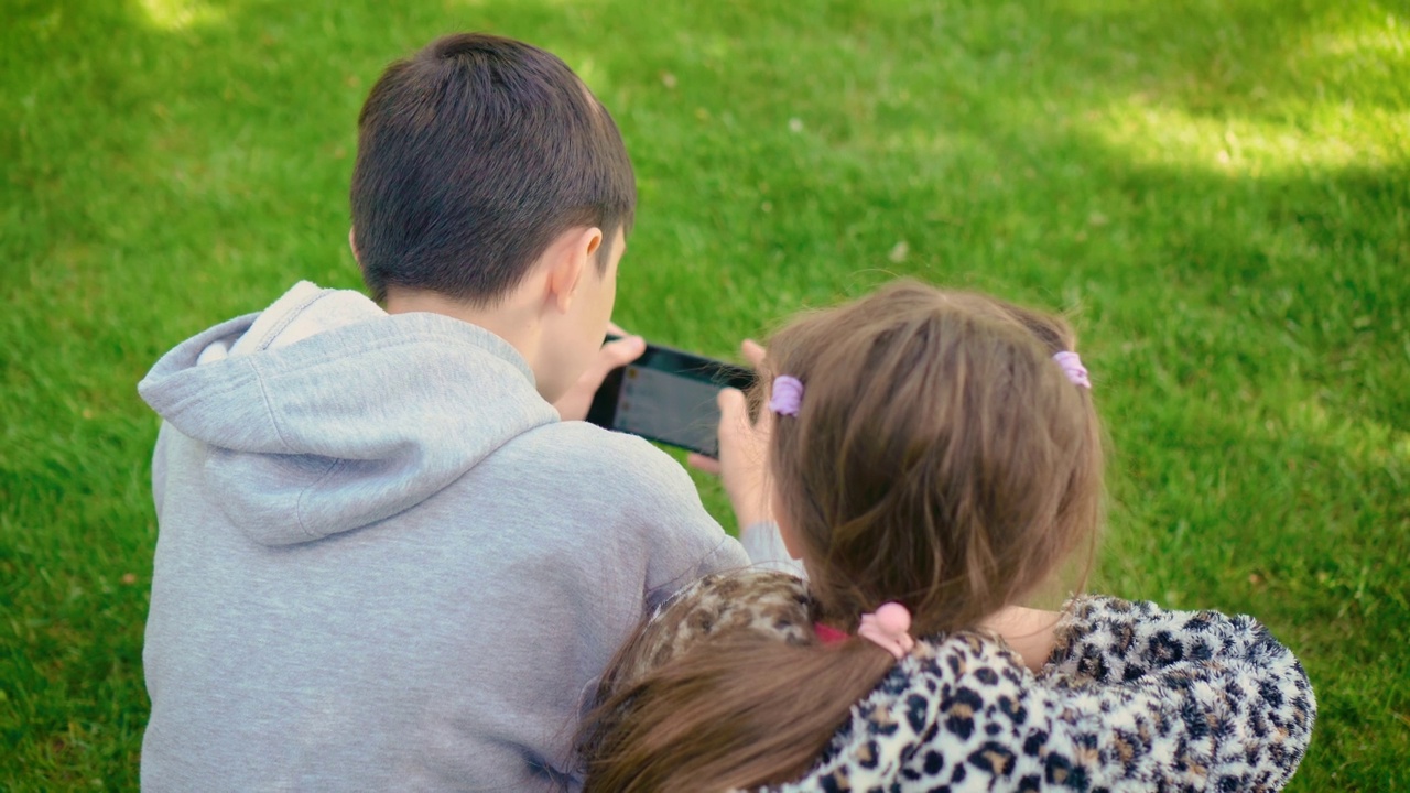 回望男孩和女孩对手机游戏的依赖。孩子们不能扔平板电脑和在户外玩耍视频素材