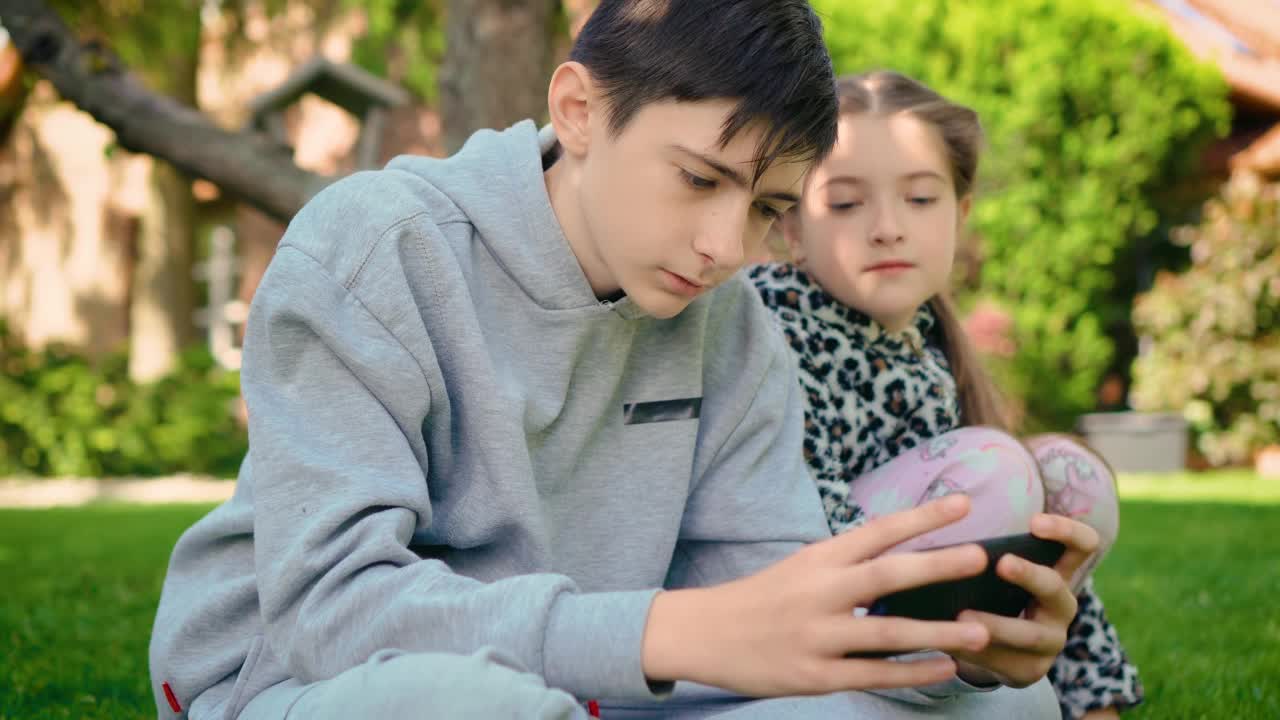 欢快的孩子们在院子里用智能手机玩手机游戏视频素材