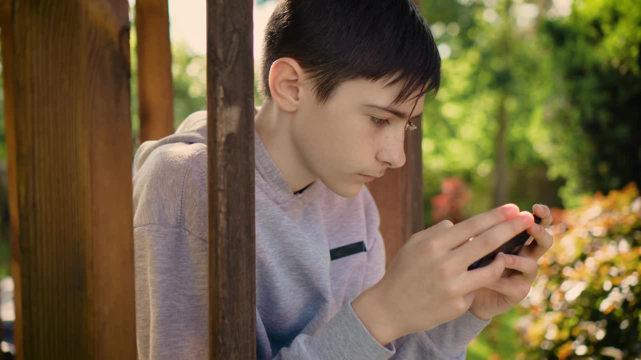 小男孩坐在木屋里用手机玩游戏视频素材