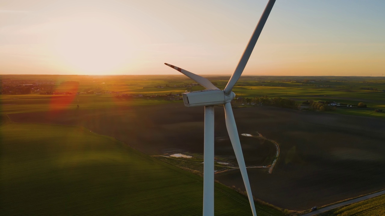 在夕阳下的绿色农田空中景观中，风车涡轮机产生清洁的可再生能源视频素材