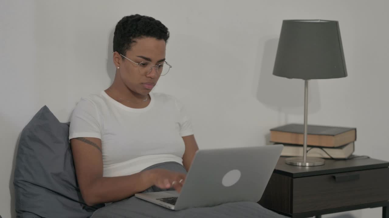 一名非洲妇女在床上使用笔记本电脑时看着相机视频素材