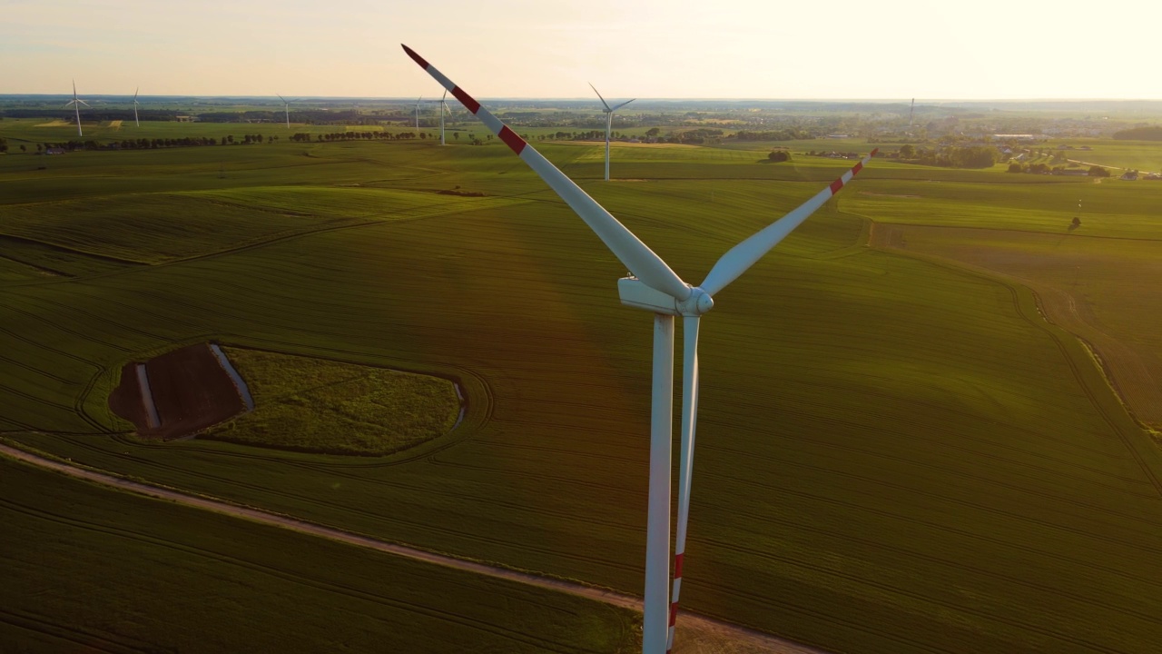在麦田中间的风力涡轮机产生可再生能源，在日落时保护环境视频素材