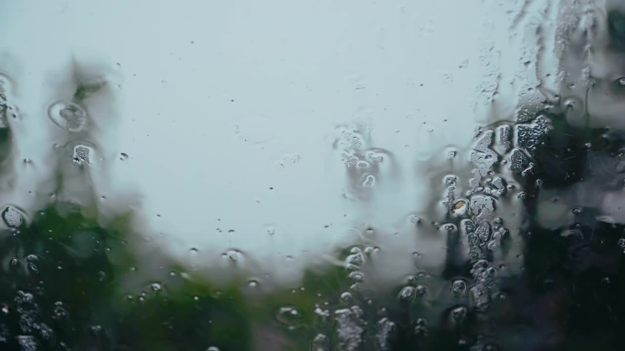 在黑暗的天空背景下，雨滴落在玻璃窗上视频素材