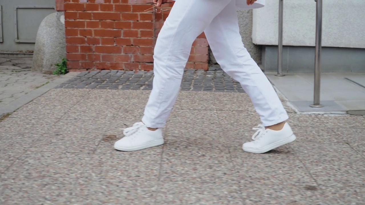 难以辨认的苗条美丽的女人穿着白色的鞋子走过城市广场视频素材