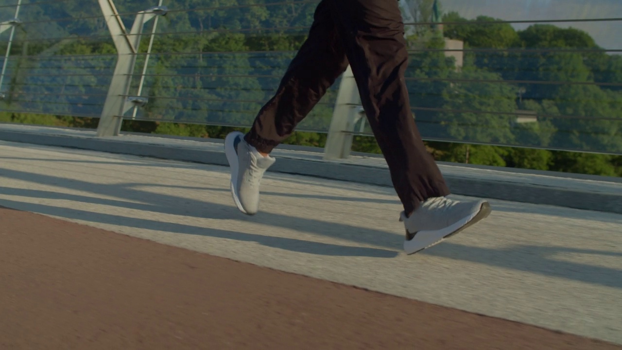 男人在日出时穿着运动鞋在桥上慢跑的特写视频素材